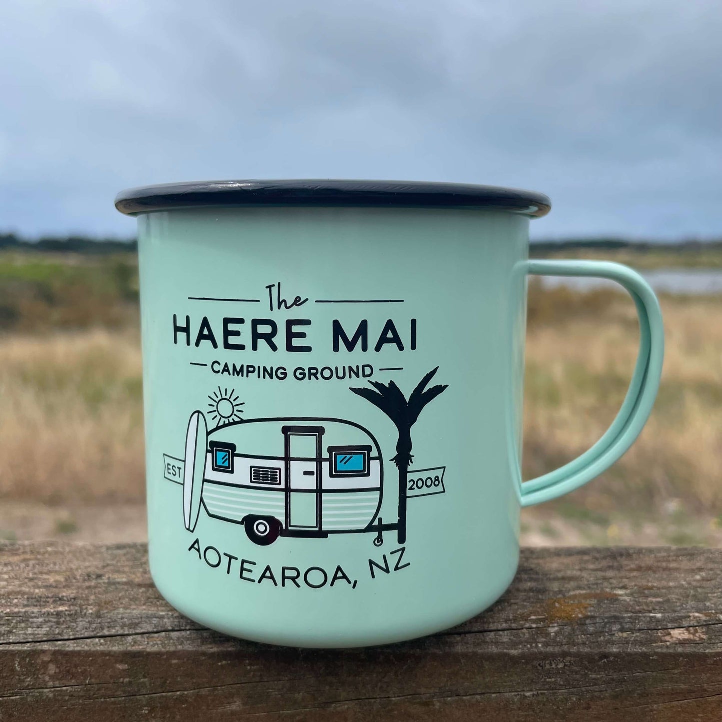 Mint green Haere Mai camping ground enamel mug with a caravan image on it.
