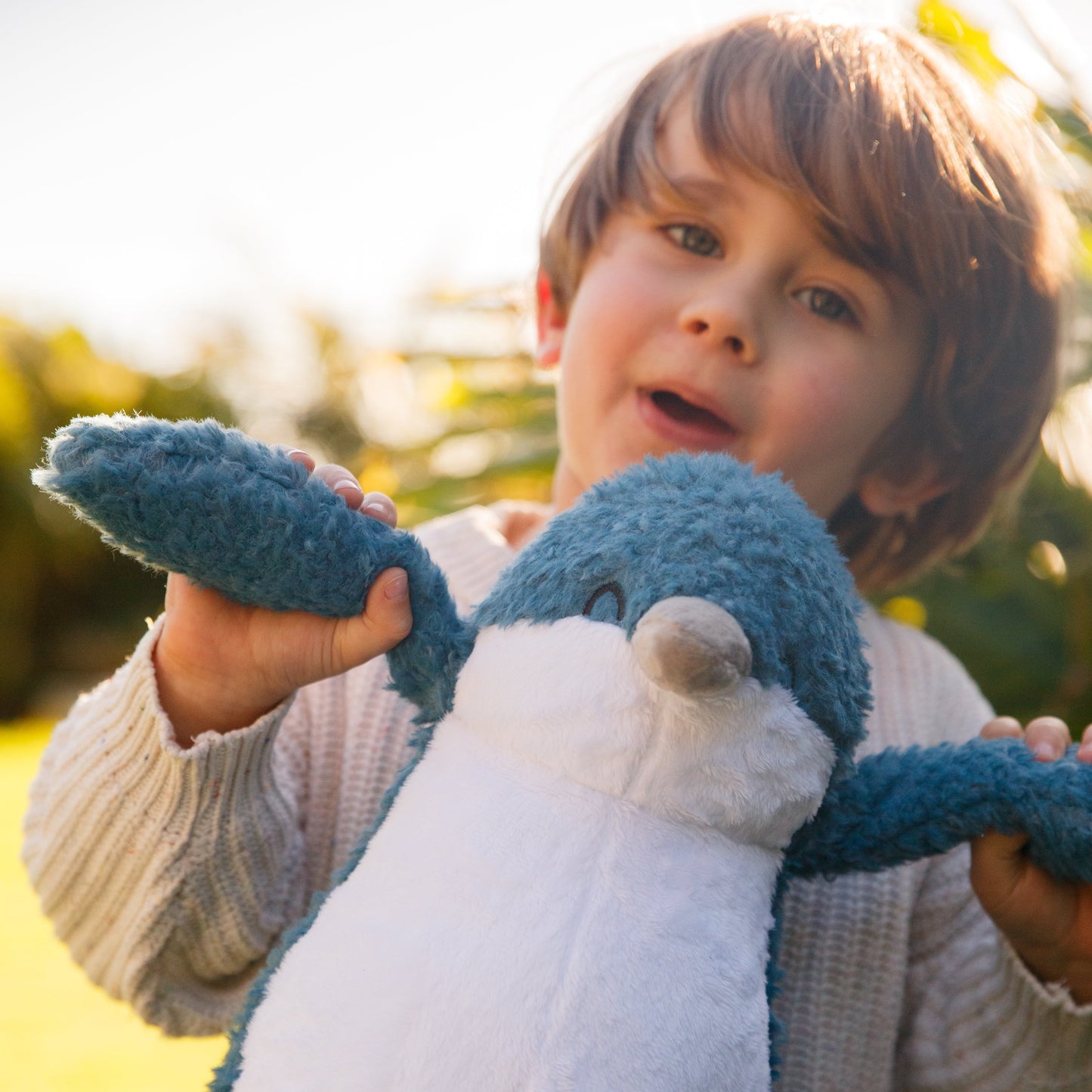 Young child holding on to a soft toy little blue penguin by its blue flippers.