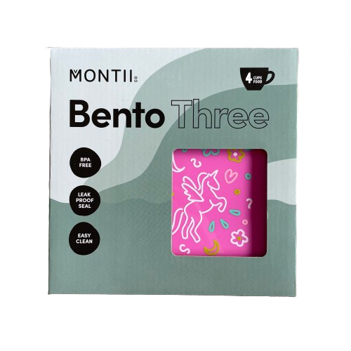 Front packaging of a MontiiCo Bento Three lunchbox showing a glimpse of the hot pink box inside with unicorn and floral print on the lid.