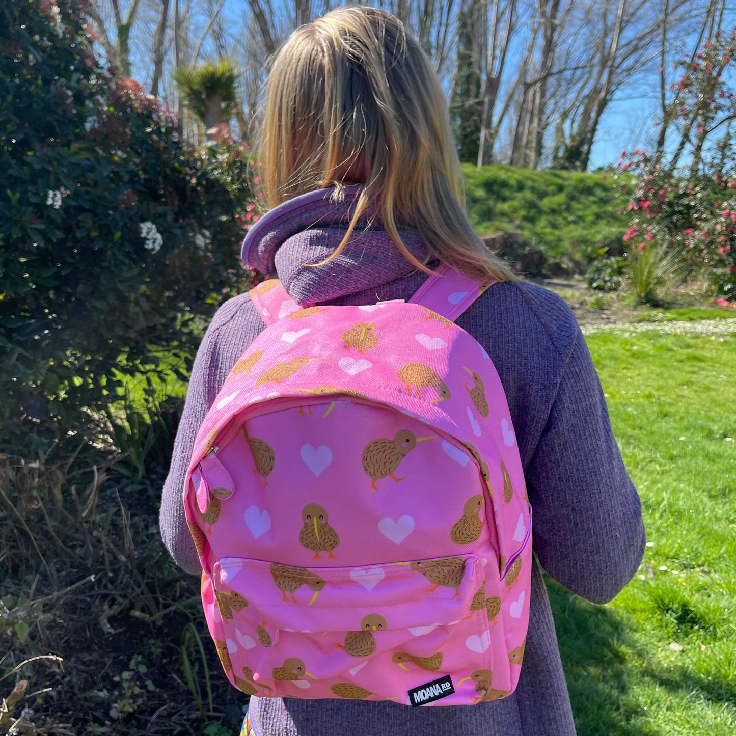 Teenager wearing a pink backpack with hearts and kiwi bird prints.