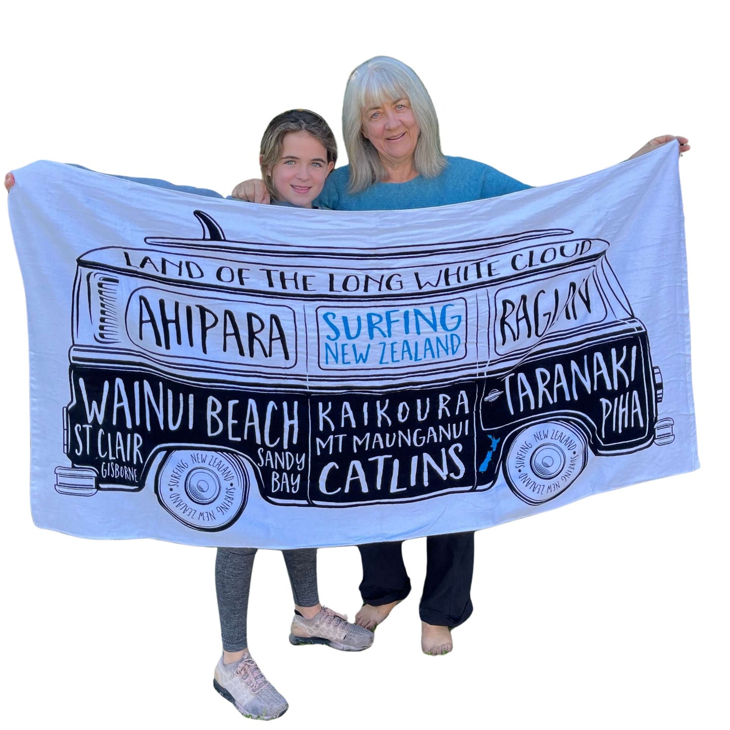 Grandmother & Grandaughter holding a large white beach towel with a Kombi van and names of New Zealand surf locations on it.