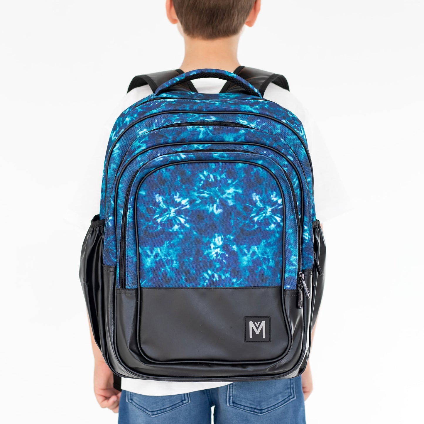 Child wearing a backpack that is blue tie dyed on the top and black base by Montiico.