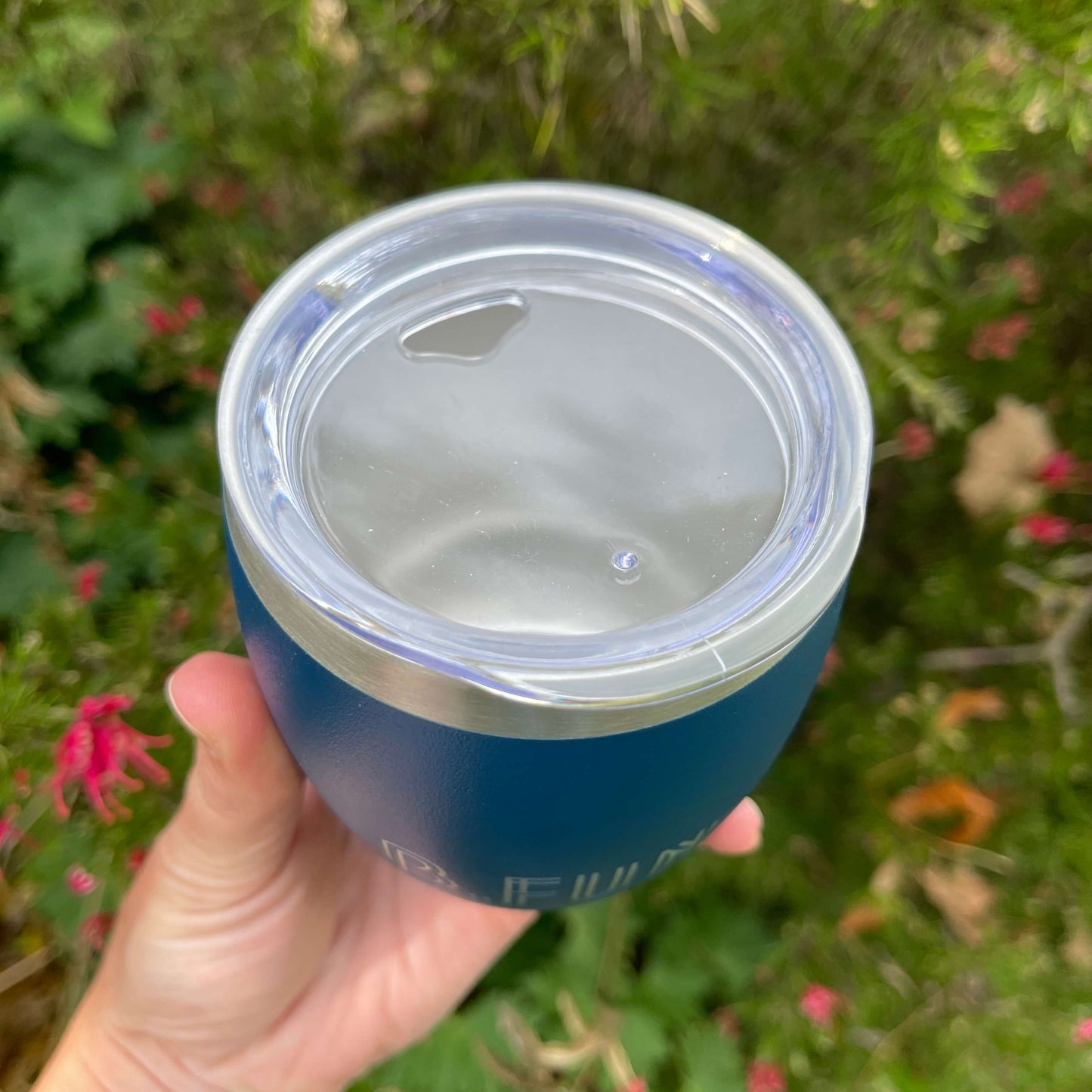Birds eye view of a stainless coffee mug featuring the clear plastic sipper top.