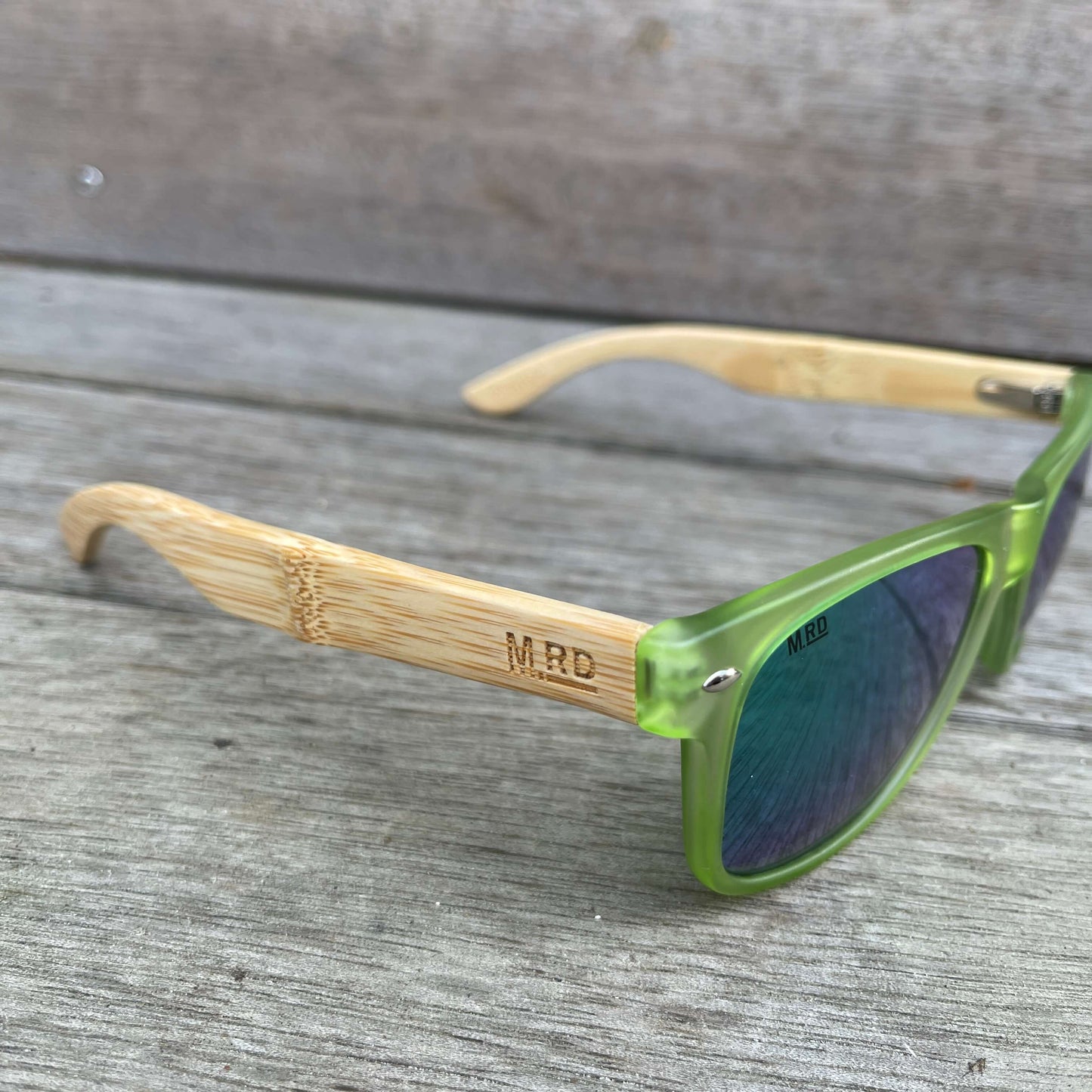 Sunglasses with wooden arms, green frames and reflective lenses.