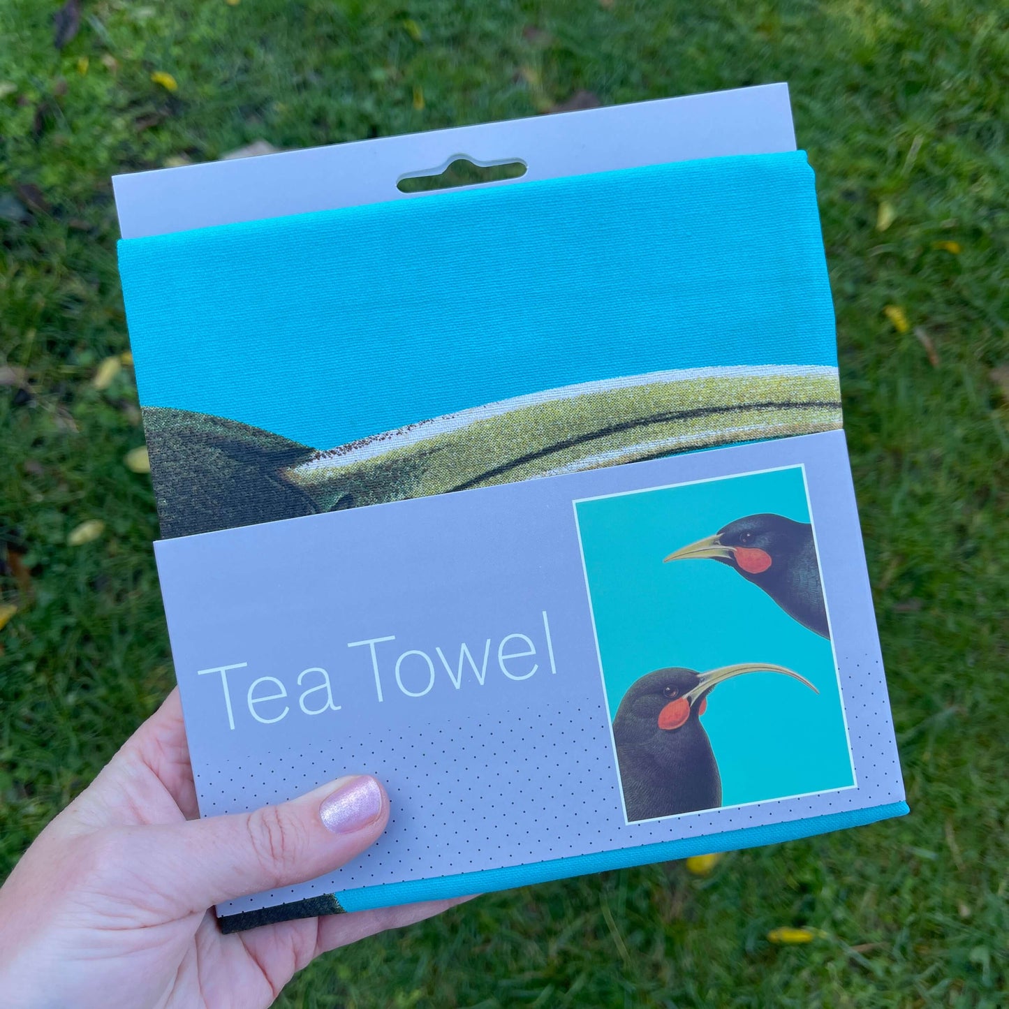 Bright blue tea towel with 2 Huia birds on it.