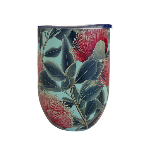A reusable insulated tumbler with a lid, featuring a botanical pattern of red pohutukawa flowers and dark green leaves on a light blue background.