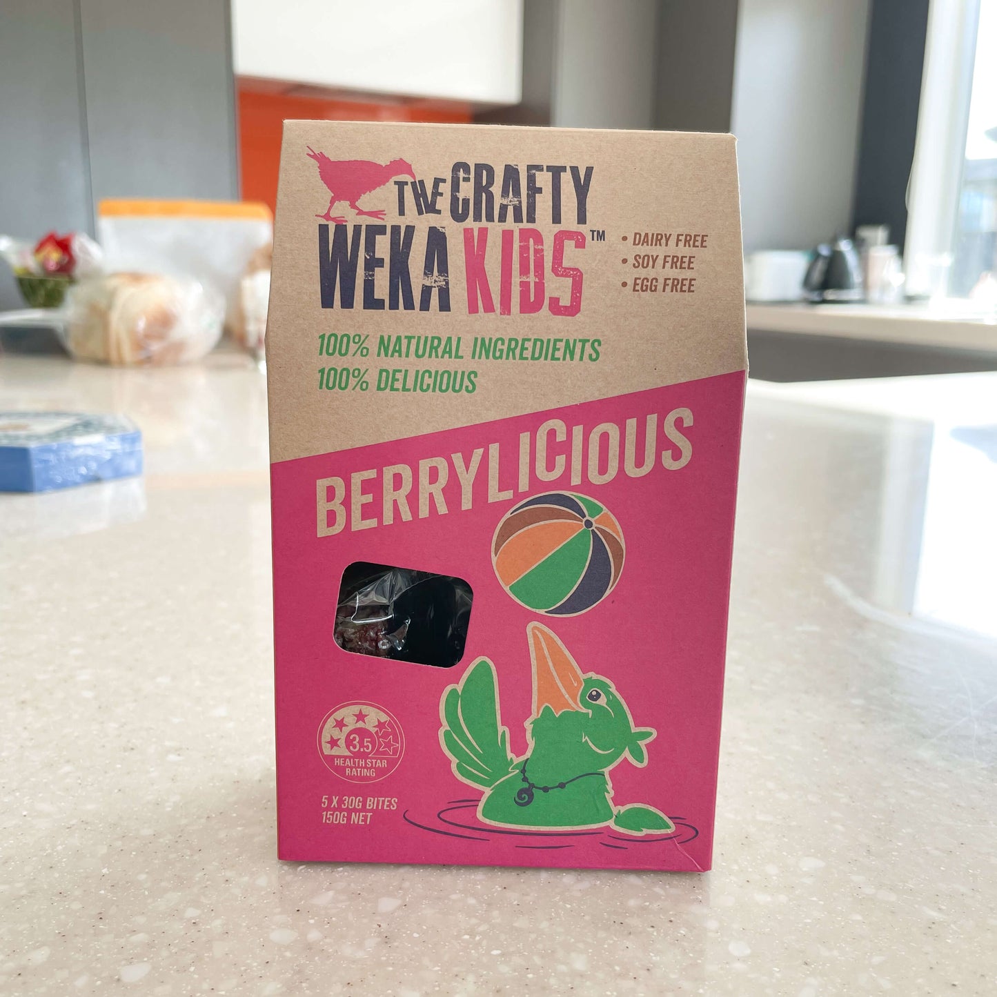 Cardboard pouch of berrylicious muesli bars from Crafty Weka sitting on a kitchen bench.