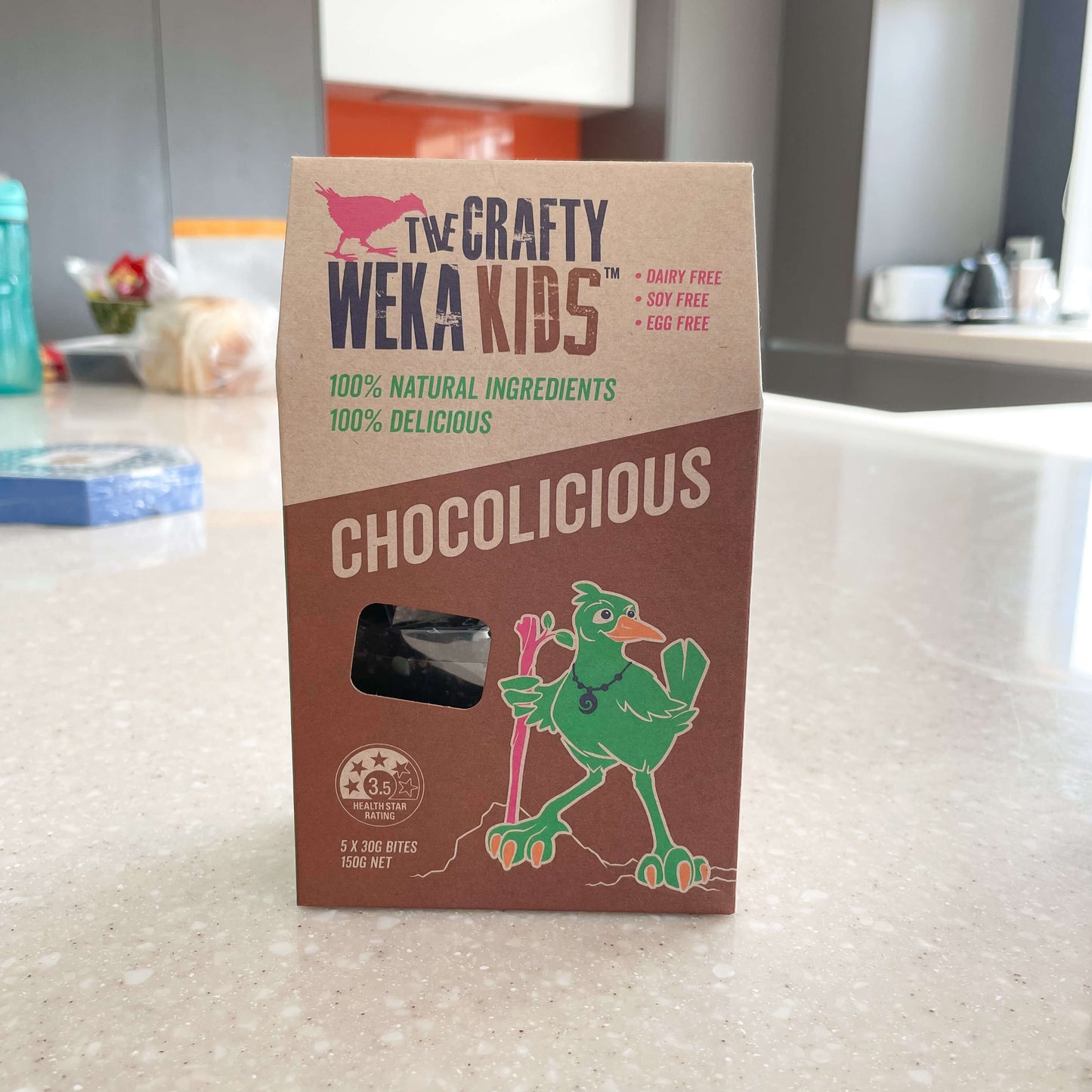 Cardboard pouch of chocolicious muesli bars from Crafty Weka sitting on a kitchen bench.