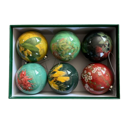 Dark green rectangle box with the lid leant up against it. In the box are 6 Christmas baubles each with a different native floral picture and colour scheme.