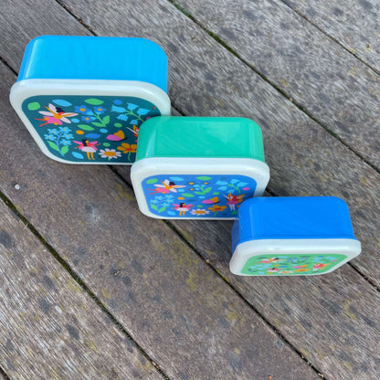 Set of 3 snack boxes in shades of blue and green with a fairy garden print on each lid.