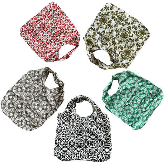 Flatlay of 5 cotton tote bags in red, olive, green, black and taupe. All with floral decorative patterns.