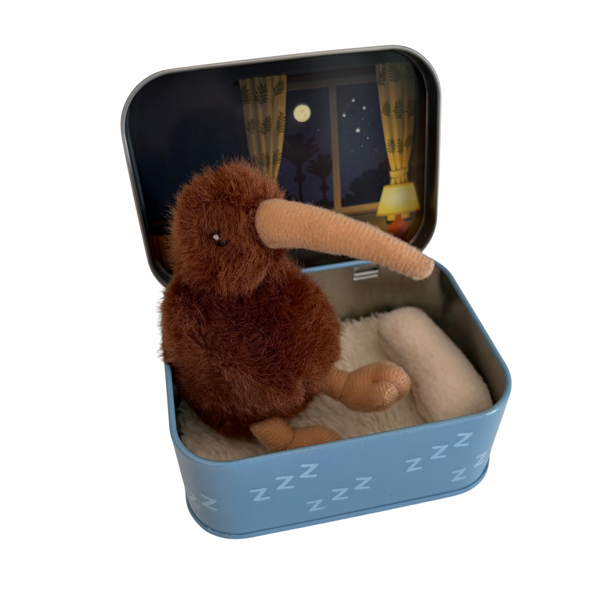 A brown plush kiwi bird toy sitting inside an open light blue metal tin with a printed night scene on the lid and white faux-fur lining. The tin has small white 'Z' symbols on the front, and the kiwi is positioned against a plain white background.