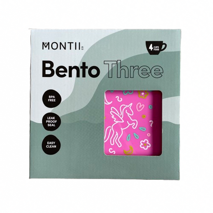 Front packaging of a MontiiCo Bento Three lunchbox showing a glimpse of the hot pink box inside with unicorn and floral print on the lid. 