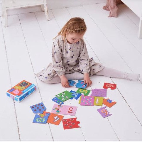 Child playing on the floor with a Peppa Pig counting puzzle.