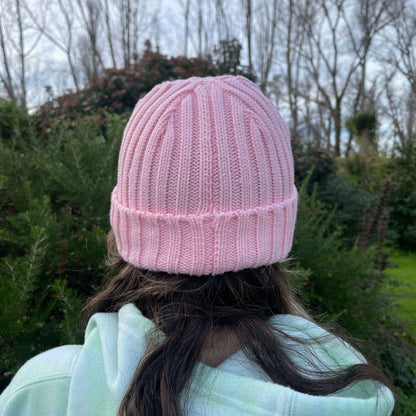 Child wearing pink knit beanie, back view.