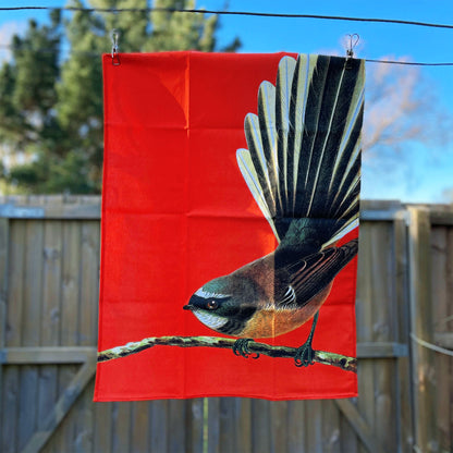 Bright orange Tea towel with a fantail on it.