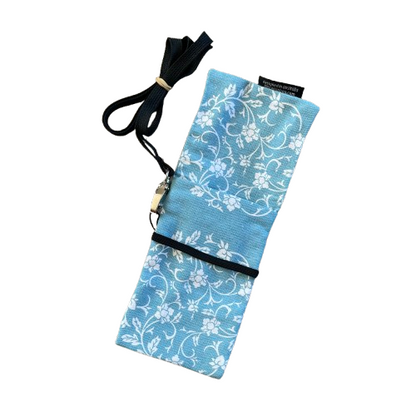 Blue phone pouch bag with white floral print and black lanyard. Pouch is opened up to show the pocket.