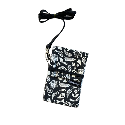 Black phone pouch bag with white floral, owl and dog print and black lanyard. 