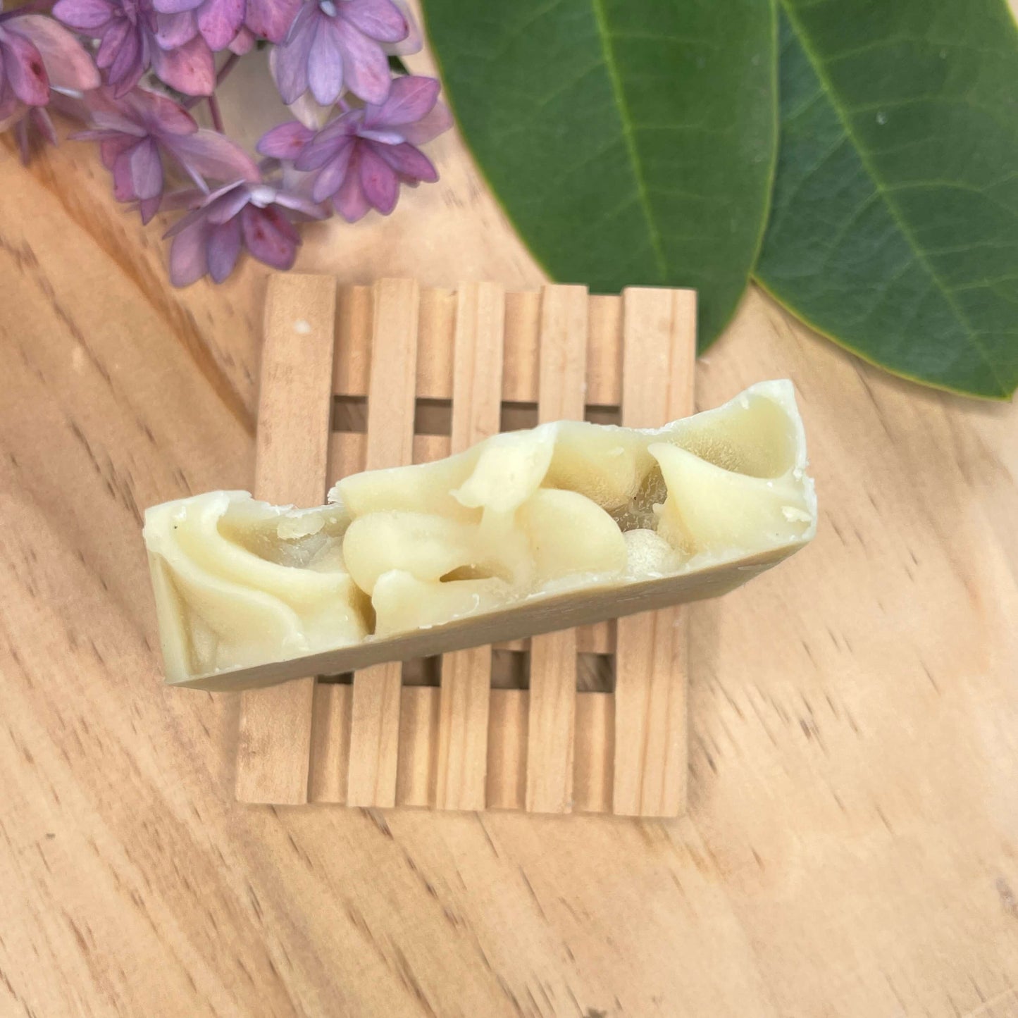 Natural shampoo bar on a wooden soap rack.