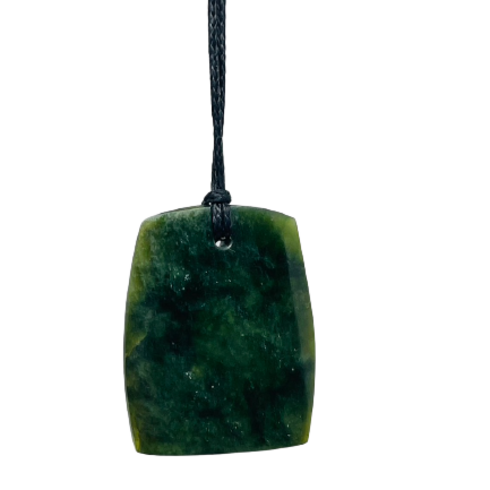 Greenstone freeform pendant on a black wax cord draped over a rock.