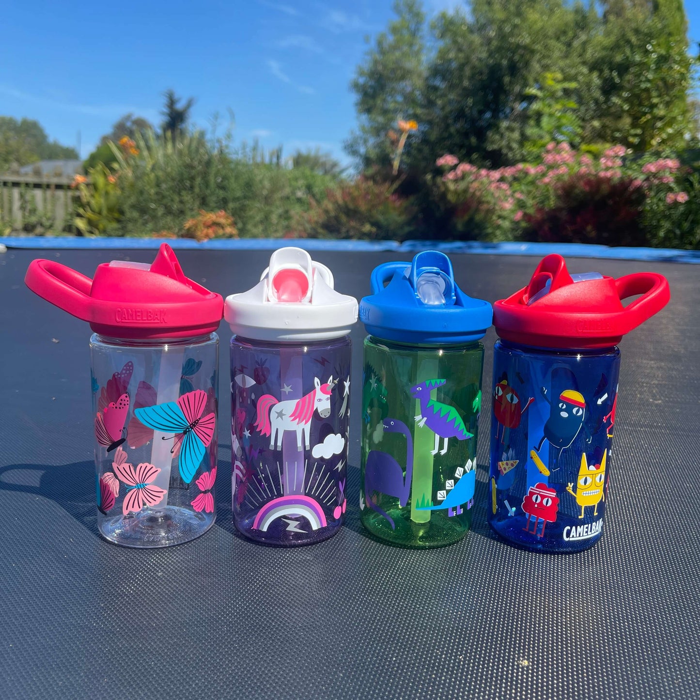 Set of four colourful kids drink bottles on a trampoline.