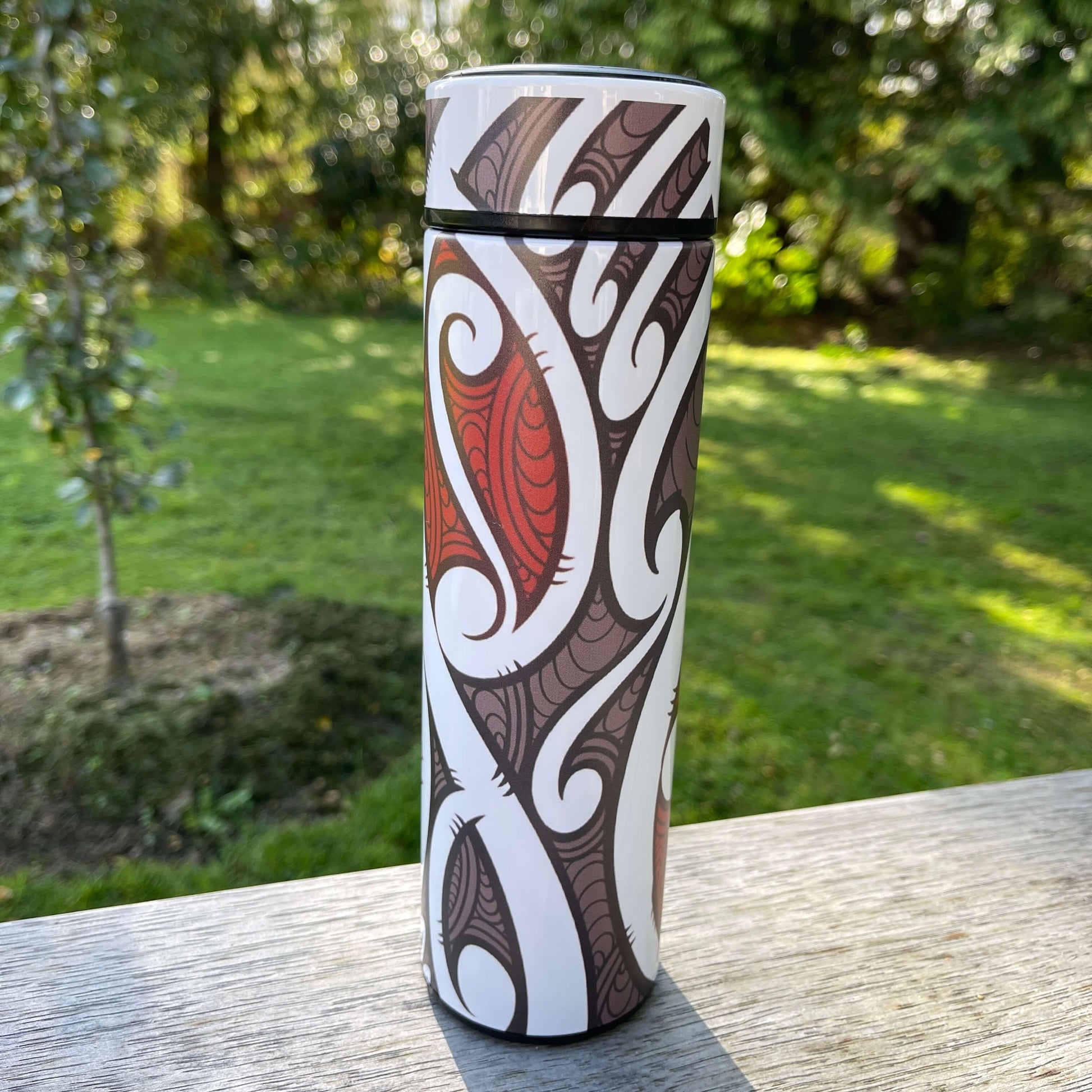 Drink bottle with black, white and red koru design.