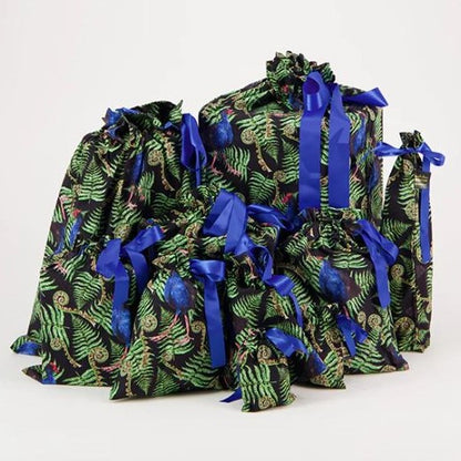 Reusable christmas gift bags with a fern and pukeko print and blue ribbon.