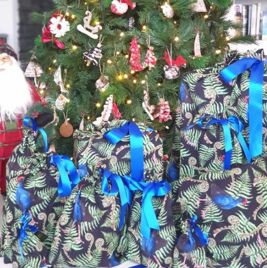 Reusable christmas gift bags with a fern and pukeko print and blue ribbon.