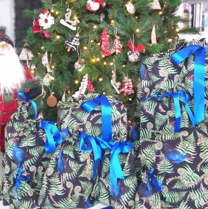 Reusable christmas gift bags with a fern and pukeko print and blue ribbon.