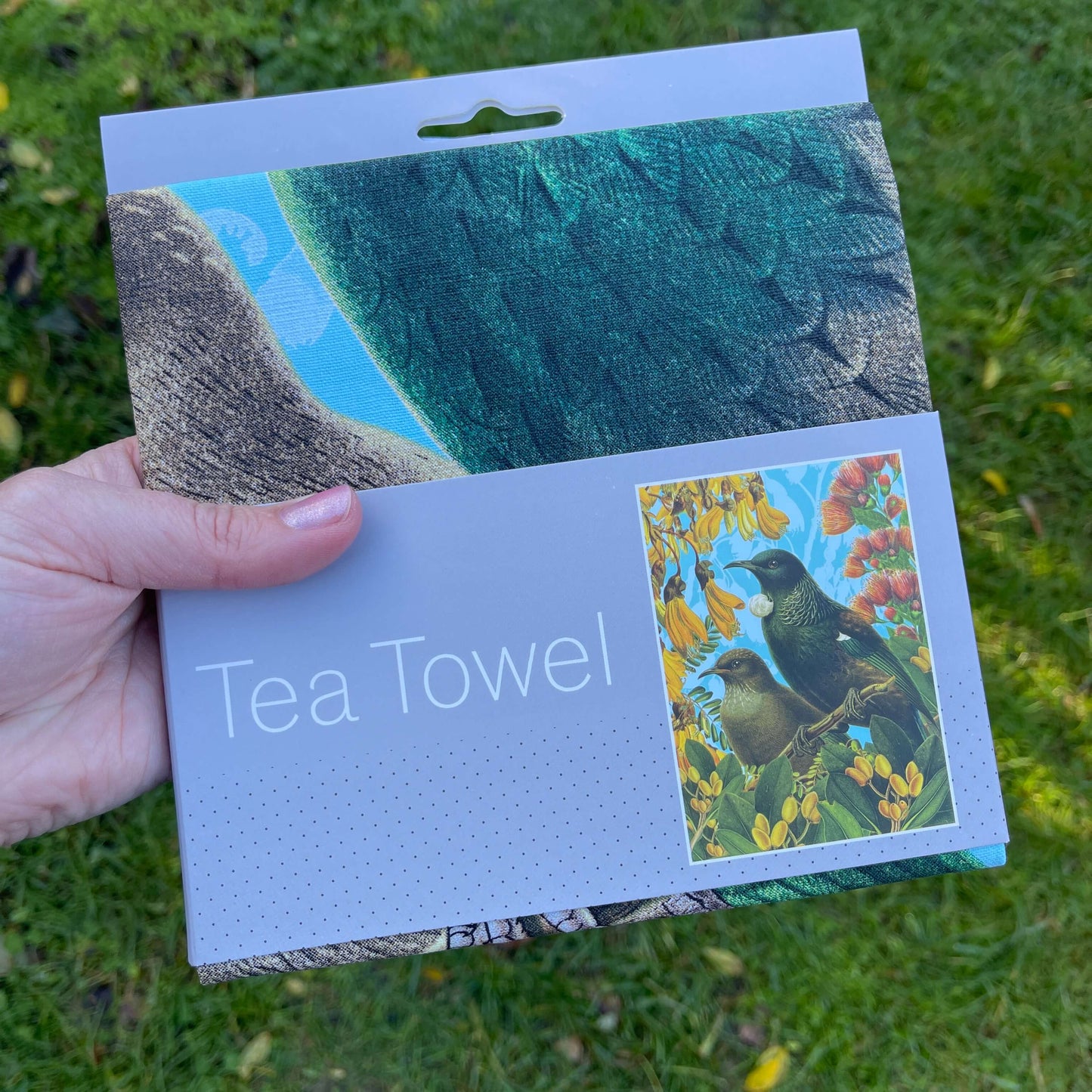 Tea towel with a Tui and flowers on it.