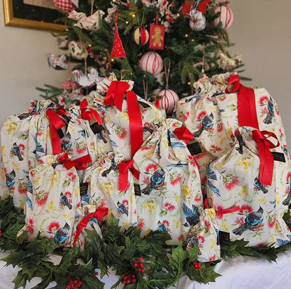 Reusable gift bags with a kiwiana flora and fauna pattern and red ribbon.